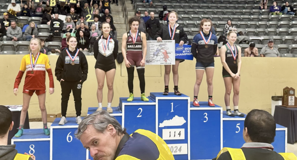 The wrestling girls stand on the podium to show where they placed.